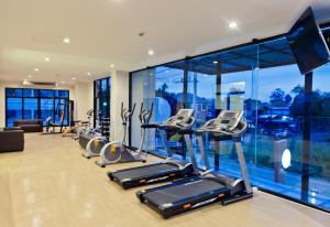 a gym with a row of cardio machines and windows at The Proud Hotel in Ubon Ratchathani