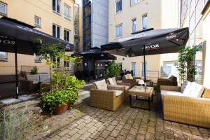 un patio con divani, tavoli e ombrelloni di Milling Hotel Gestus ad Aalborg