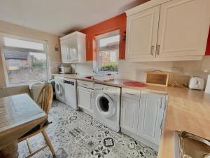 a kitchen with white cabinets and a washer and dryer at GuestReady-Close To Leeds City, Spacious, Sleeps 6 in Leeds
