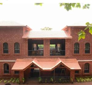 un gran edificio de ladrillo rojo con balcón en Konkan Nest Resort, en Ganpatipule