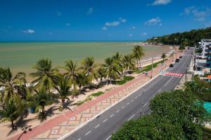 a road next to a beach with palm trees at Setai Yacht Premium - By Almare Flats in João Pessoa