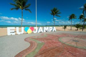 a sign in front of a beach with palm trees at Setai Yacht Premium - By Almare Flats in João Pessoa