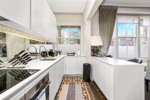 una cucina con banconi bianchi e una grande finestra di Stunning 3 Bed Apartment- Paddington a Londra