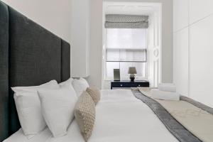 una camera bianca con un grande letto con cuscini bianchi di Stunning 3 Bed Apartment- Paddington a Londra