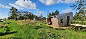 a small wooden cabin in a field with a fence at Tiny House De Skries in Westergeest +12 photos