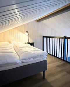 a bed with white sheets and a lamp in a room at Skaidi Luxury Lodge – Heart of the Arctic in Hammerfest