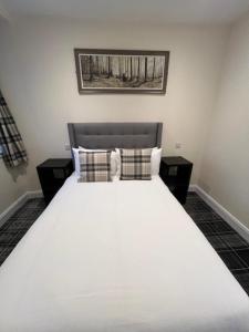 1 dormitorio con 1 cama blanca grande con almohadas en Waverley Inn Lodge, en Dingwall