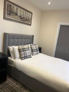 a bedroom with a large bed with white sheets and pillows at Waverley Inn Lodge in Dingwall