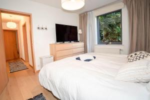 - une chambre avec un grand lit blanc et une fenêtre dans l'établissement Appartement très lumineux de 120m2, à Bruxelles