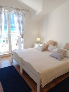 a white bed in a room with a large window at Apartments Laura Mljet in Sobra