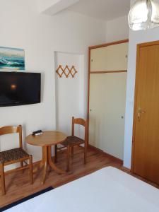 a room with a table and chairs and a television at Apartments Laura Mljet in Sobra