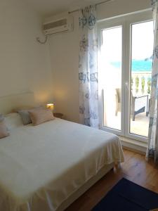 een slaapkamer met een bed en een groot raam bij Apartments Laura Mljet in Sobra