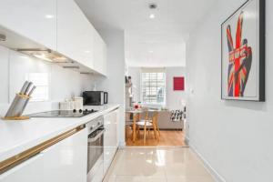 uma cozinha com armários brancos e um forno com placa de fogão em Luxurious 3 Bedroom Flat in Haymarket London Sleeps 14 HY1 em Londres