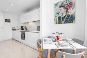 uma cozinha branca com uma mesa e cadeiras brancas em Luxurious 3 Bedroom Flat in Haymarket London Sleeps 14 HY1 em Londres