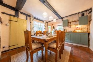 a kitchen with a wooden table and a kitchen with green cabinets at Medieval cottage in rural village - Duke's Lodge in Bildeston