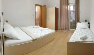 a bedroom with two beds with white sheets at Apartments Ruzinka in Podaca