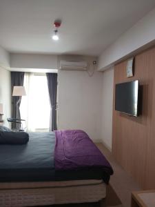 Schlafzimmer mit einem Bett und einem Flachbild-TV in der Unterkunft Hani Apartemen Simpang lima in Semarang