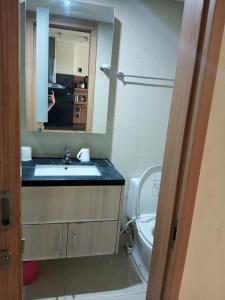 ein Badezimmer mit einem Waschbecken, einem WC und einem Spiegel in der Unterkunft Hani Apartemen Simpang lima in Semarang