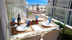 a table with plates and wine glasses on a balcony at Apartamento frente al mar in Cullera