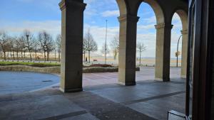 an archway with columns in a building with the ocean in the background at Sunshine beach Gijón in Gijón