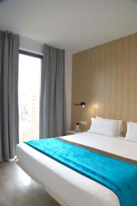 バルセロナにあるコスモ アパートメンツ コンセル デ セント プラサ ウニベルシタットの大きな窓付きの客室の大型ベッド1台分です。