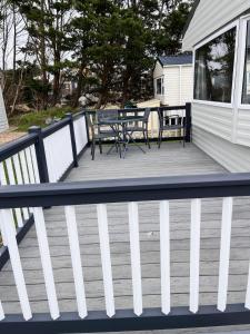 a deck with a table and chairs on a house at Rye Harbour Holiday Park in Rye Harbour