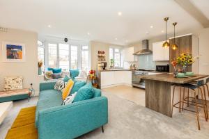 a living room with a blue couch and a kitchen at Exquisite 1BR in Chiswick, 3 min to Train Station in London