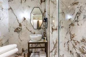 Baño de mármol con lavabo y espejo en Acca Hotel en Venecia