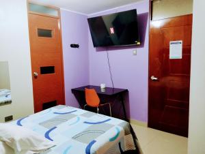 1 dormitorio con 1 cama, escritorio y TV en HOSTAL TOSCANO SUITES, en El Tambo