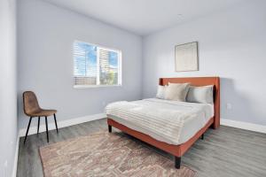 een witte slaapkamer met een bed en een stoel bij NoHo by AvantStay North Hollywood Townhome in Los Angeles