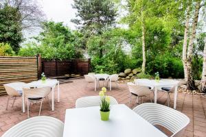 eine Terrasse mit weißen Tischen, Stühlen und Bäumen in der Unterkunft Select Hotel Erlangen in Erlangen