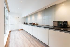 uma cozinha com armários brancos e um micro-ondas em Luxury 2 Bedroom Flat in Bell Street em Londres