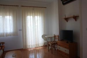 a living room with a television and a table with chairs at Apartamentos turisticos Andrew´s in Puerto de Mazarrón