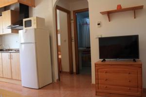a kitchen with a refrigerator and a tv on a dresser at Apartamentos turisticos Andrew´s in Puerto de Mazarrón +3 photos