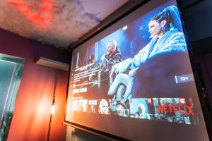a large screen with a movie on the wall at Capsule cloud - jacuzzi - projecteur cinema in Tourcoing