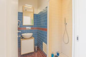 Baño de azulejos azules con lavabo y espejo en B&B Salerno Centrale, en Salerno