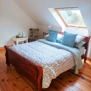 Un dormitorio con una cama con almohadas azules y una ventana en Country Lane Homestay, en Westport