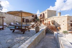 a patio with wooden tables and an umbrella at Stone Court Boutique Studios in Paphos City