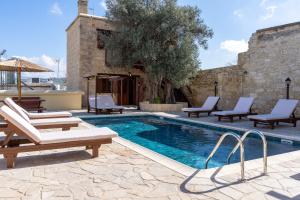 a swimming pool with chaise lounges and chairs next to a building at Stone Court Boutique Studios in Paphos