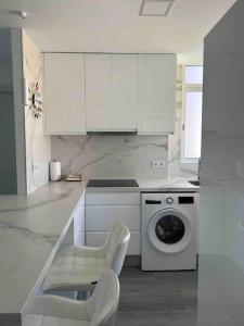 cocina blanca con lavadora y silla en Elegante Loft en San Juan Playa, en Alicante