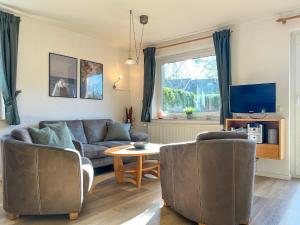 een woonkamer met een bank en stoelen en een tv bij Urlauberdorf Haus 51a in Boltenhagen