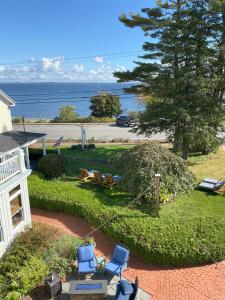 a house with chairs and a yard with the ocean at Spouter Inn Bed & Breakfast in Lincolnville