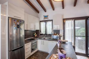 a kitchen with a stainless steel refrigerator and white cabinets at The Gift Sani Villa in Sani Beach