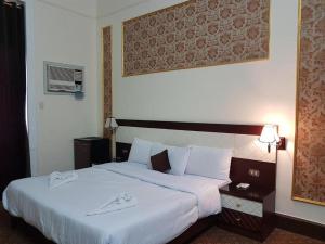 una habitación de hotel con una cama grande con sábanas blancas en Cairo Paradise Hotel, en El Cairo
