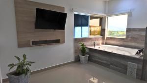 ein Badezimmer mit einer Badewanne und einem TV an der Wand in der Unterkunft Hotel La Gran Estaciónag in Armenia