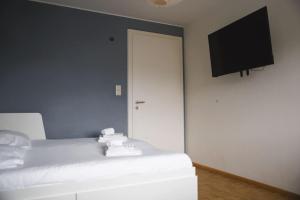 - une chambre avec un lit blanc et une télévision à écran plat dans l'établissement Cozy 3 bedroom house with 11 kw electric car charger, à Hesperange
