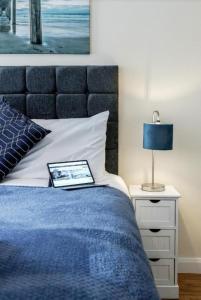 a bed with a blue blanket and a lamp on a night stand at Zs Apartments - St Albans City Centre - 20 mins from London in St. Albans