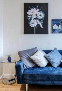 a blue couch in a living room with a picture of flowers at Zs Apartments - St Albans City Centre - 20 mins from London in St. Albans