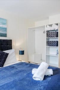 a bedroom with a blue bed with towels on it at Zs Apartments - St Albans City Centre - 20 mins from London in Saint Albans