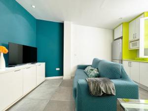 a living room with a blue couch and a tv at Luminoso, con patio y buena zona in Madrid